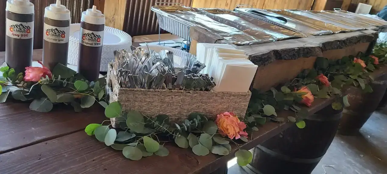 Buffet serving setup with Colorado Q sauces and greenery at a previous event